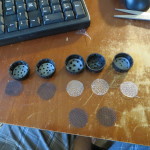 Cutting small circles from preforated plastic lid and window screen to lay inside 2 litter caps